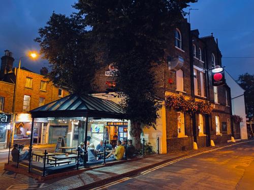 a group of people sitting in a bus stop on a street at The Red Cow - Guest House in Richmond upon Thames