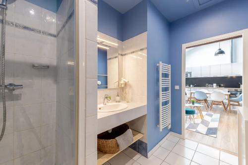 La salle de bains est pourvue de murs bleus, d'un lavabo et d'une douche. dans l'établissement Aux portes de Bordeaux Le Patio Samba MindUrGuest, à Bègles