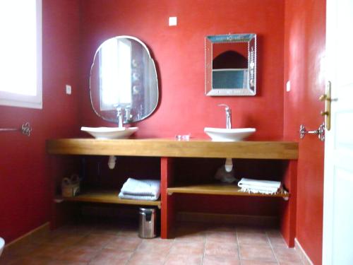 - une salle de bains rouge avec deux lavabos et un miroir dans l'établissement Un coin de campagne à 4km de la mer pour 4 à 6 personnes, à Portiragnes