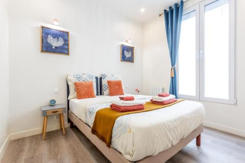 une chambre avec un lit et une fenêtre avec des rideaux bleus dans l'établissement StayLib - Chic and Cosy 2 rooms porte de Montmartre, à Saint-Ouen