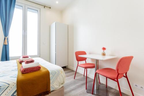 une chambre avec un lit, deux chaises et une table dans l'établissement StayLib - Chic and Cosy 2 rooms porte de Montmartre, à Saint-Ouen