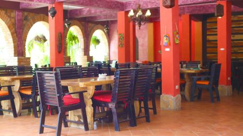 une salle à manger avec des tables, des chaises et des colonnes rouges dans l'établissement Hotel Ciudad Blanca, à Copan Ruinas