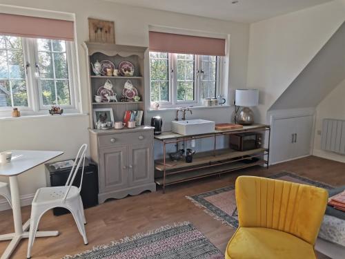 a kitchen with a sink and a table and a chair at The Suffolk Cartlodge 