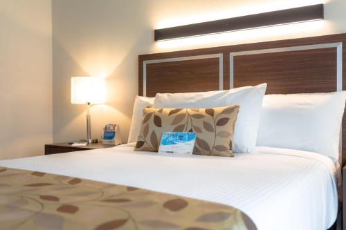 a bedroom with a large white bed with a lamp at Sleep Inn Guadalajara Galerias in Guadalajara