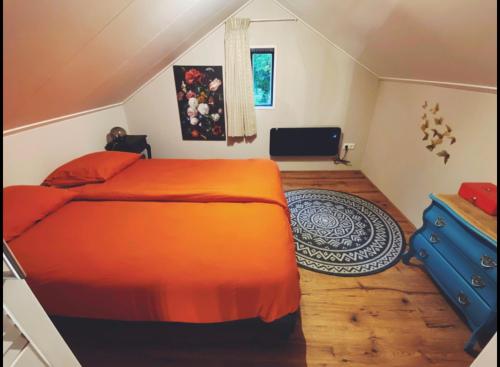 a bedroom with a large orange bed and a blue dresser at Vakantieverblijf Perron 3 in Haarle