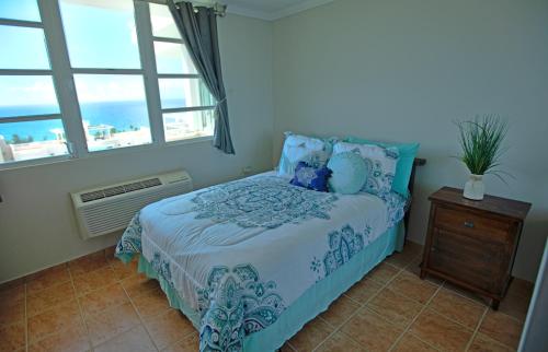 Schlafzimmer mit einem Bett mit blauer Bettwäsche und einem Fenster in der Unterkunft Oceanview Lighthouse Villa in Maunabo