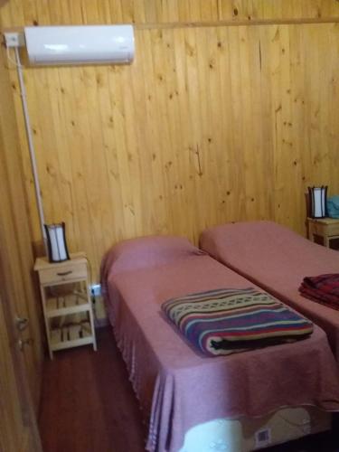 two beds in a room with wooden walls and wooden floors at Chacra Mandala in Gualeguay
