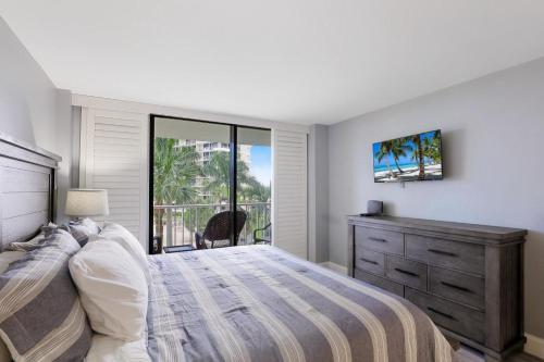 Un dormitorio con una cama y una cómoda y una ventana. en Beachfront condo with heated pool, gym and pickleball, en Marco Island