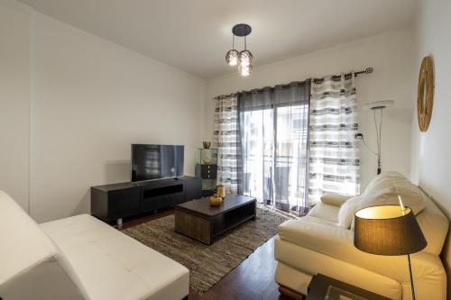 ein Wohnzimmer mit einem Sofa und einem TV in der Unterkunft City View Apartment by Madeira Sun Travel in Funchal