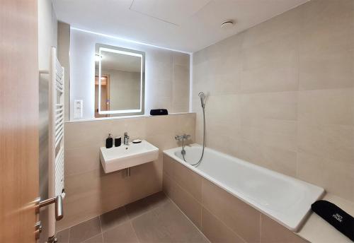 ein Badezimmer mit einem Waschbecken, einer Badewanne und einem Spiegel in der Unterkunft New modern 2 bedrooms apartment in Bratislava in Bratislava