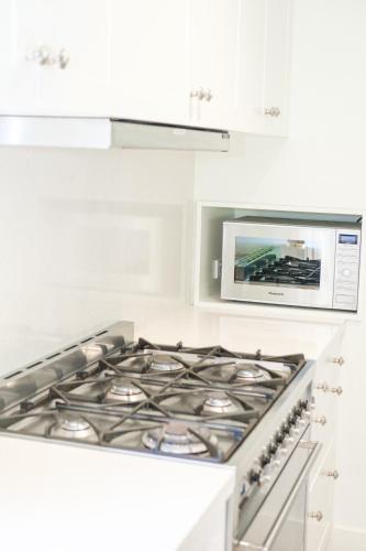 a stove top oven in a kitchen with a microwave at Sandalwood in Avoca Beach