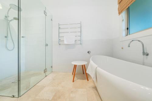 a bathroom with a tub and a glass shower at Sandalwood in Avoca Beach