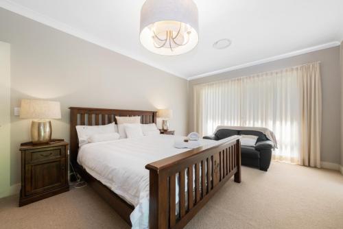a bedroom with a large bed and a chair at Sandalwood in Avoca Beach