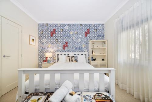 a white crib in a childs bedroom with blue wallpaper at Sandalwood in Avoca Beach