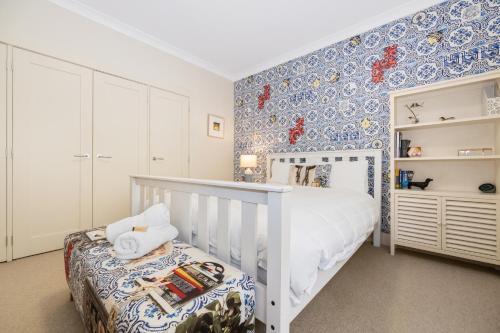 a bedroom with a white crib and blue and white wallpaper at Sandalwood in Avoca Beach