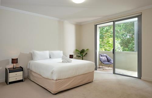 Habitación blanca con cama y balcón. en Warrawee Premium 2 Bed Apartment w Large Balcony and Secure Parking en Warrawee