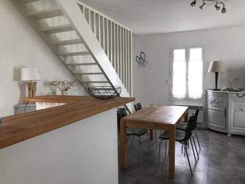 a kitchen and dining room with a table and a staircase at St Mart. l'îlot Rhéa in Saint-Martin-de-Ré