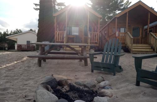 a picnic table and chairs in front of a cabin at Beach House Lakeside Cottages in Mackinaw City