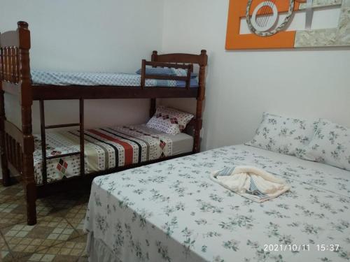 イーリャ・コンプリーダにあるHospedagem Familiar Yamaneの二段ベッド2台、テーブル付きのベッド1台が備わる客室です。