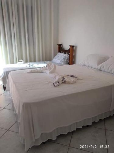 two beds in a bedroom with white sheets at Hospedagem Familiar Yamane in Ilha Comprida