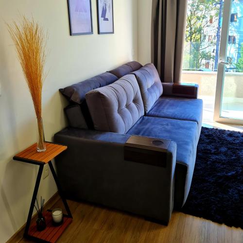 a living room with a blue couch and a table at Loft Gramado in Gramado