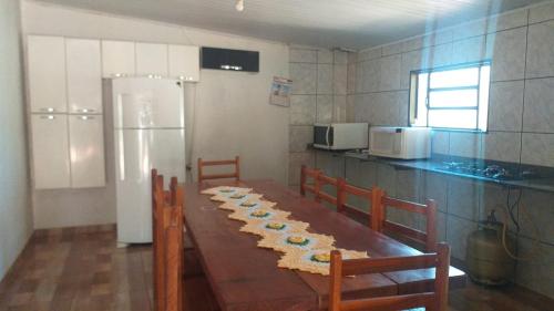 a kitchen with a table with chairs and a refrigerator at Chácara São Francisco in Olímpia