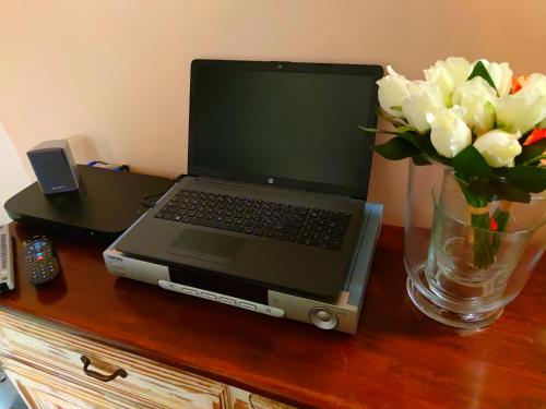 a laptop computer sitting on a table with a vase of flowers at Dimora Arco Basso - Old Town in Bari