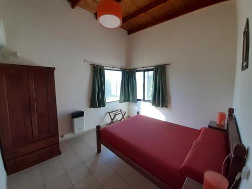 a bedroom with a red bed and two windows at Ayres Del Rio Uruguay in Colón