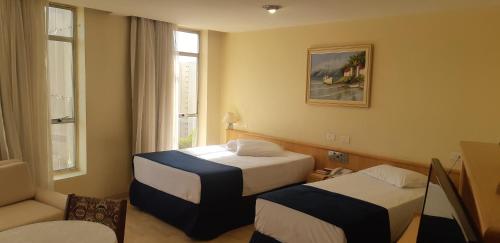 a hotel room with two beds and a couch at Pampas Palace Hotel in São Bernardo do Campo