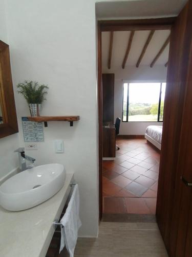 a bathroom with a sink and a room with a bedroom at Casa del Sol in Villa de Leyva