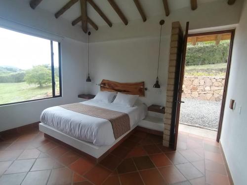 Un dormitorio con una cama y una ventana grande. en Casa del Sol, en Villa de Leyva