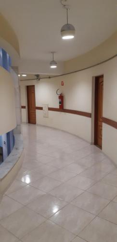 a large room with a white tile floor and wooden doors at Pampas Palace Hotel in São Bernardo do Campo
