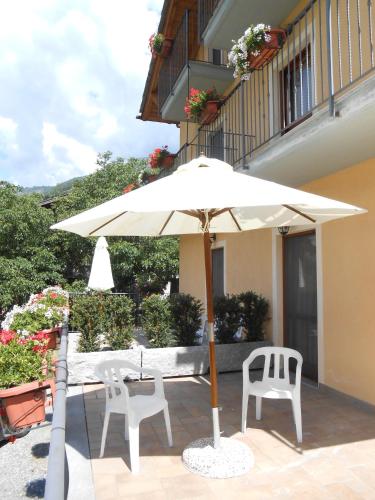 a white umbrella and two chairs on a patio at Affittacamere Les Noyers in Verrayes