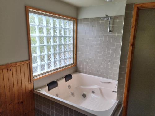 a bath tub in a bathroom with a window at D'Altons Studios in Halls Gap