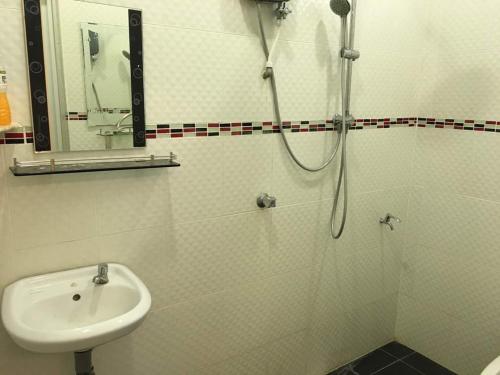 uma casa de banho branca com um chuveiro e um lavatório. em Homestay Atfa Beseri Kangar Perlis em Kangar