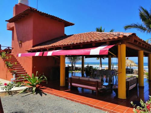 einen Pavillon mit einer Bank, einem Tisch und Stühlen in der Unterkunft Casa La Quinta Ola in Troncones