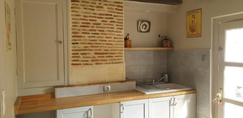 cocina con fregadero y pared de ladrillo en La petite maison en Saint-Aignan