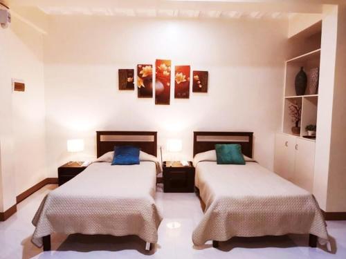 a bedroom with two beds and paintings on the wall at MS Residence Building in Lucban