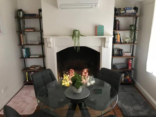 a living room with a table and chairs and a fireplace at Cornelias Cottage Mount Gambier Central in Mount Gambier