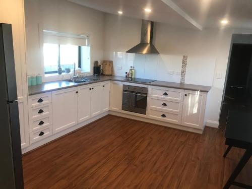 a kitchen with white cabinets and a wooden floor at Cornelias Cottage Mount Gambier Central in Mount Gambier