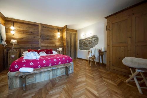 a bedroom with a large bed with red sheets and white shoes at Le Relais du Boucher in Gaby