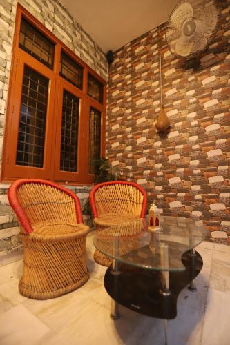a patio with two chairs and a table and a brick wall at Karta-Purakh an Ayurvedic Stay in Amritsar