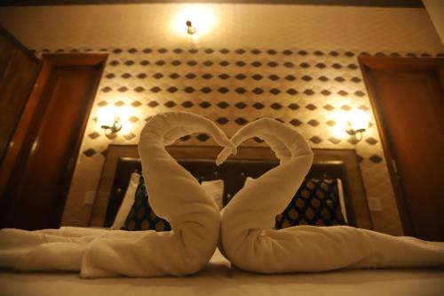 two towels in the shape of a heart on a bed at Karta-Purakh an Ayurvedic Stay in Amritsar