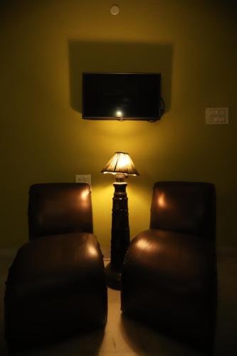 a living room with a lamp and two chairs at Karta-Purakh an Ayurvedic Stay in Amritsar