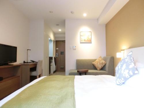 a hotel room with a bed and a couch and a television at Tokyu Stay Yoga in Tokyo