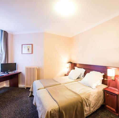 カレーにあるメトロポール ホテルのベッドとデスクが備わるホテルルームです。