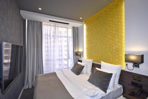 a bedroom with a large bed with a yellow wall at Avenue ApartHotel in Yerevan