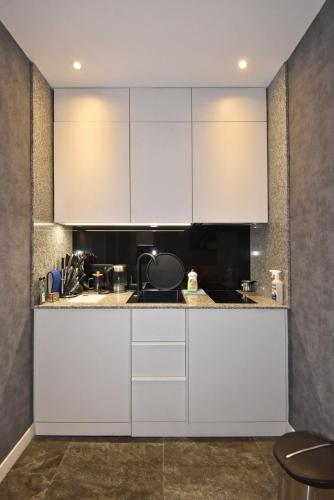 a kitchen with white cabinets and a sink at Avenue ApartHotel in Yerevan