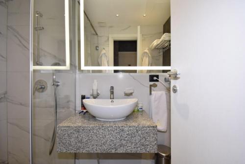 a bathroom with a white sink and a shower at Avenue ApartHotel in Yerevan