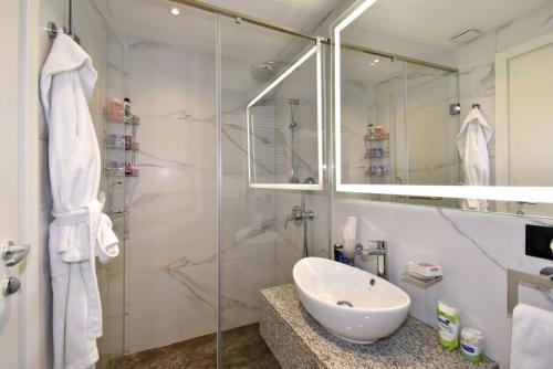 a bathroom with a sink and a glass shower at Avenue ApartHotel in Yerevan
